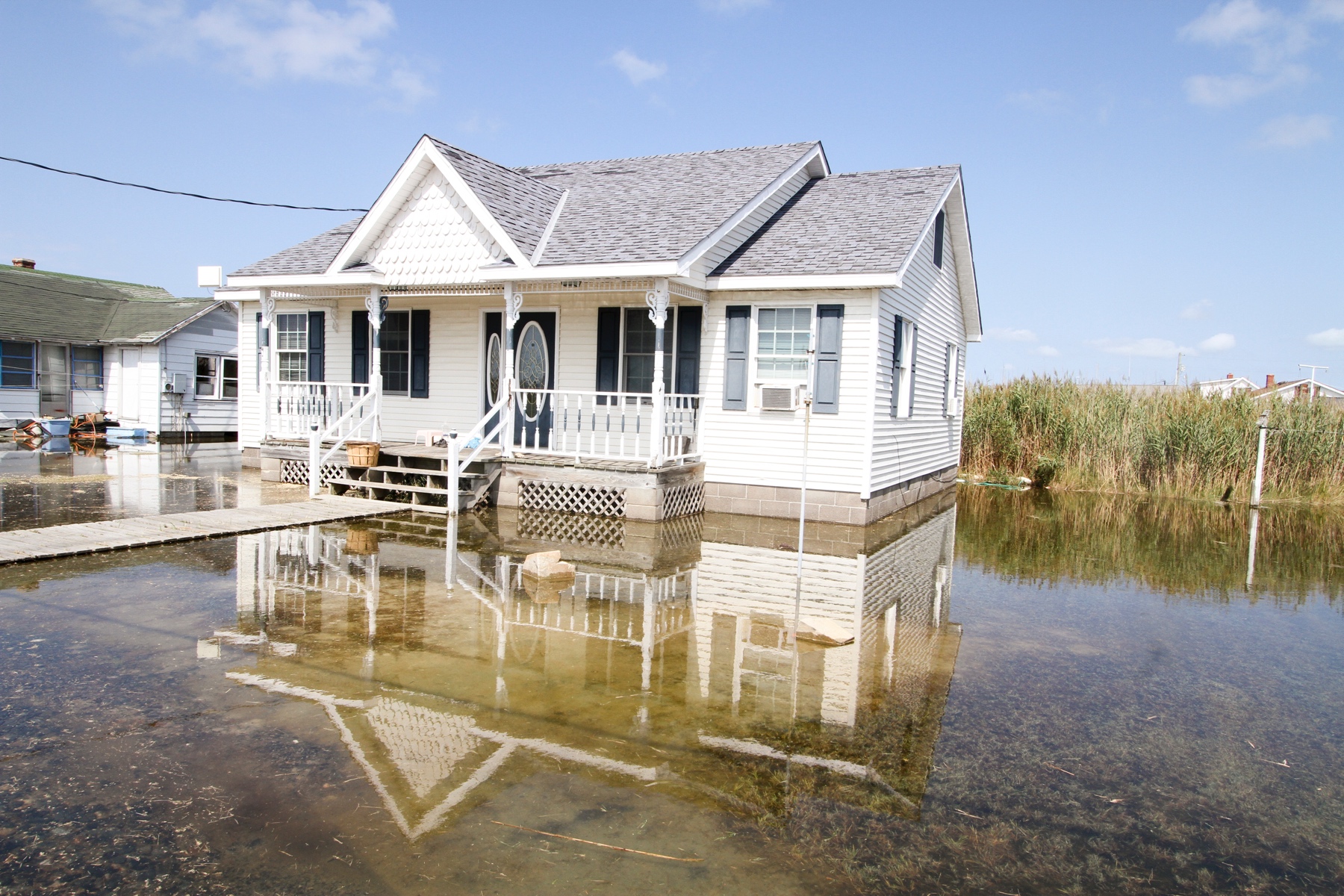 Town of Tangier occupied housing showing flooding at spring tide and recent precipitation. Note that the house and walkway to the house are both raised, the yard of the property is wetlands. Source: USACE, Norfolk District, Patrick Bloodgood, photographer.
