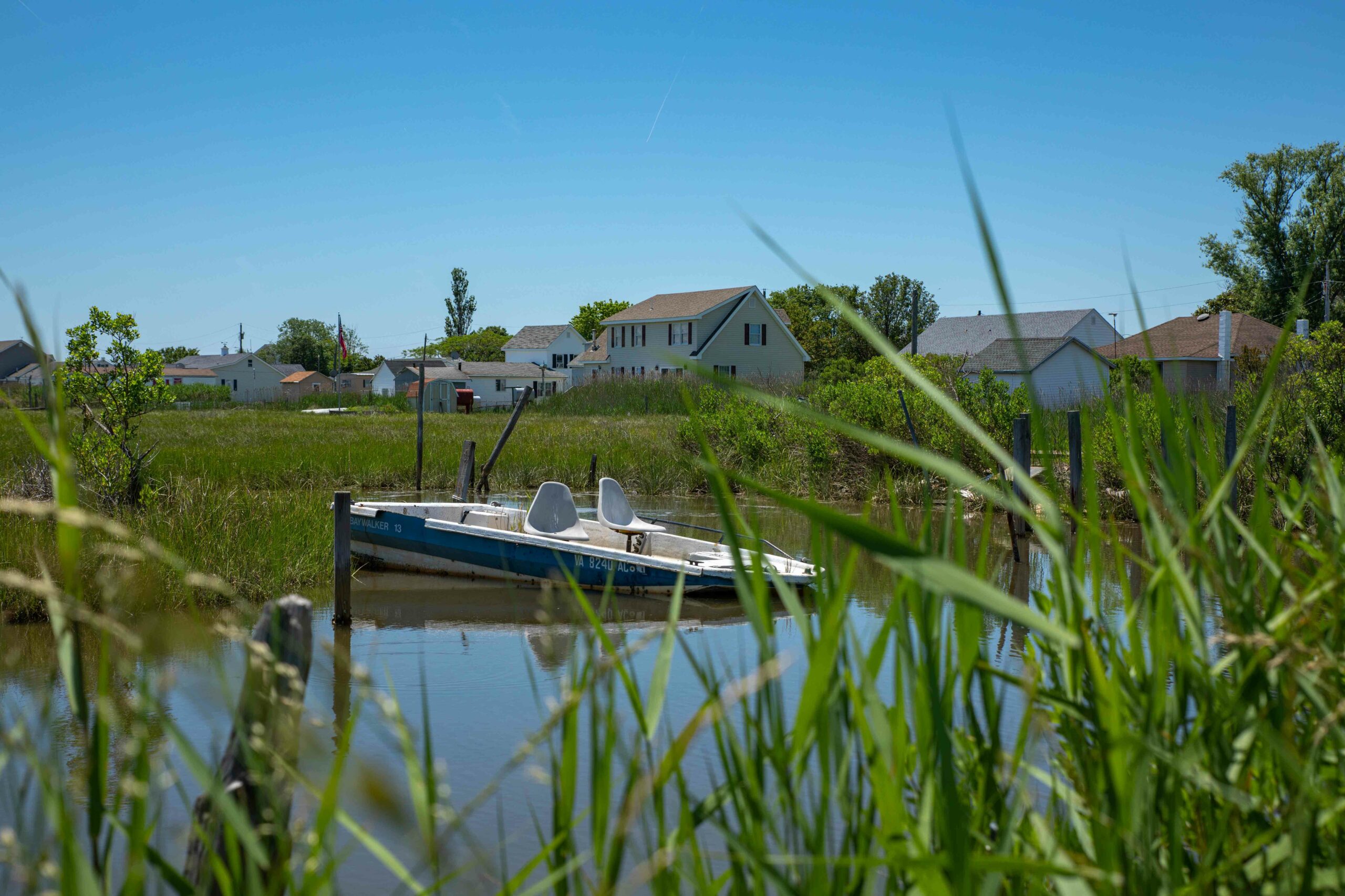 A boat docked in the creek behind some homes | VPM COM