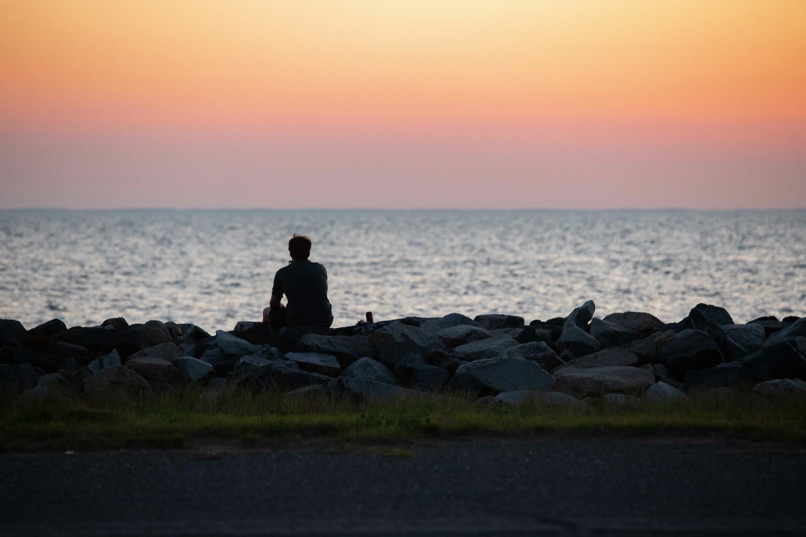 Man sitting on the west side jetty watching sunset | VPM COM